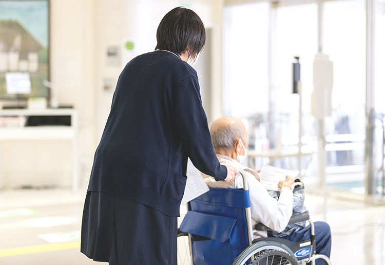 車いすのおじいさんと、それを押している職員